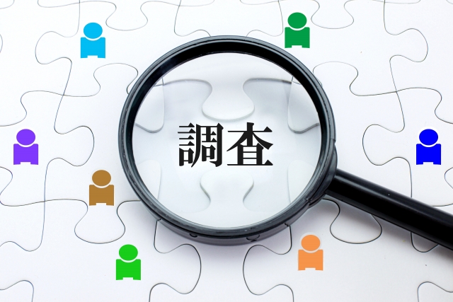 パズルの上にある調査の文字と虫眼鏡